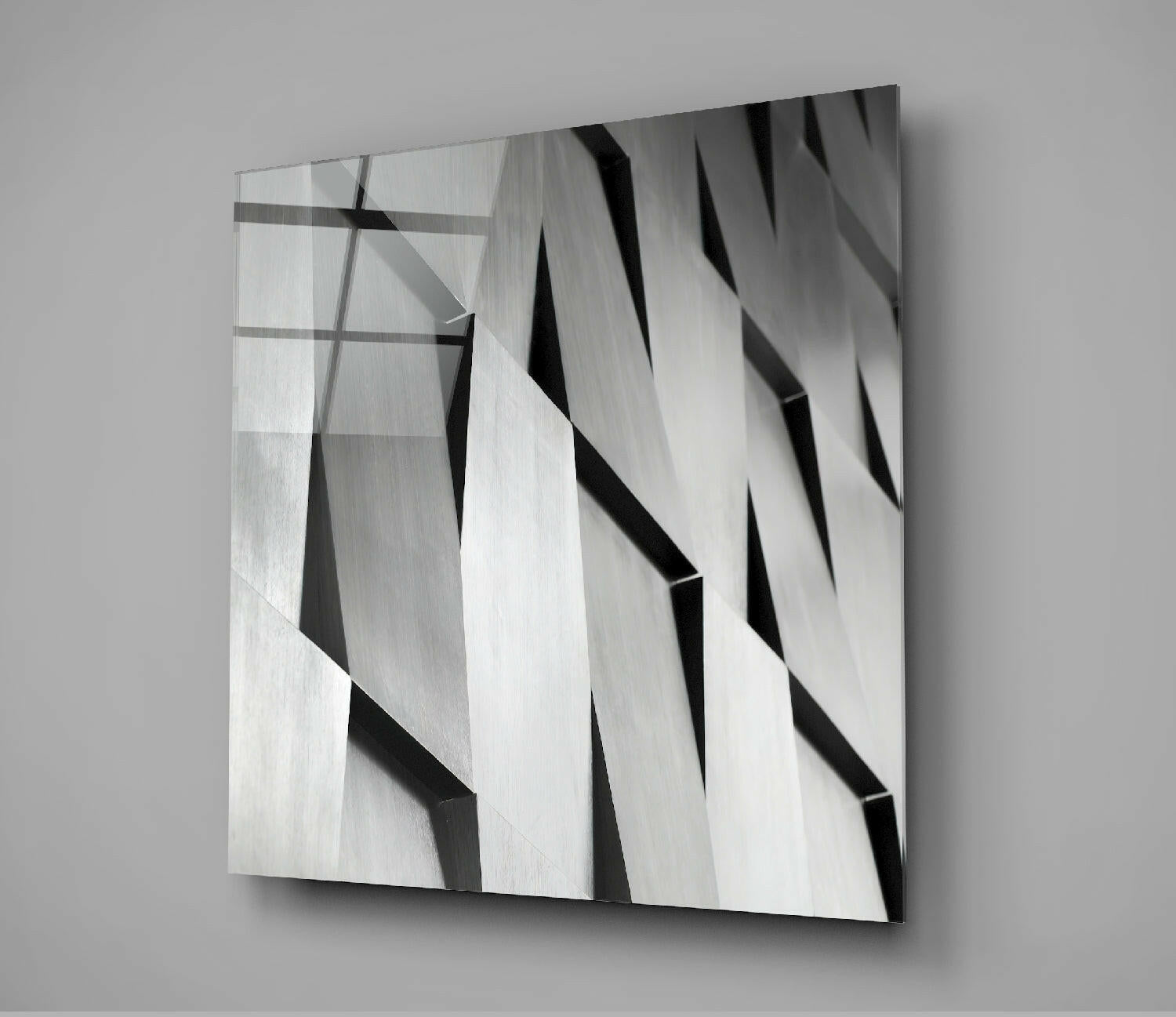 Modern abstract glass wall art with diagonal black and white striped pattern and layered dimensional effect, mounted on gray wall.