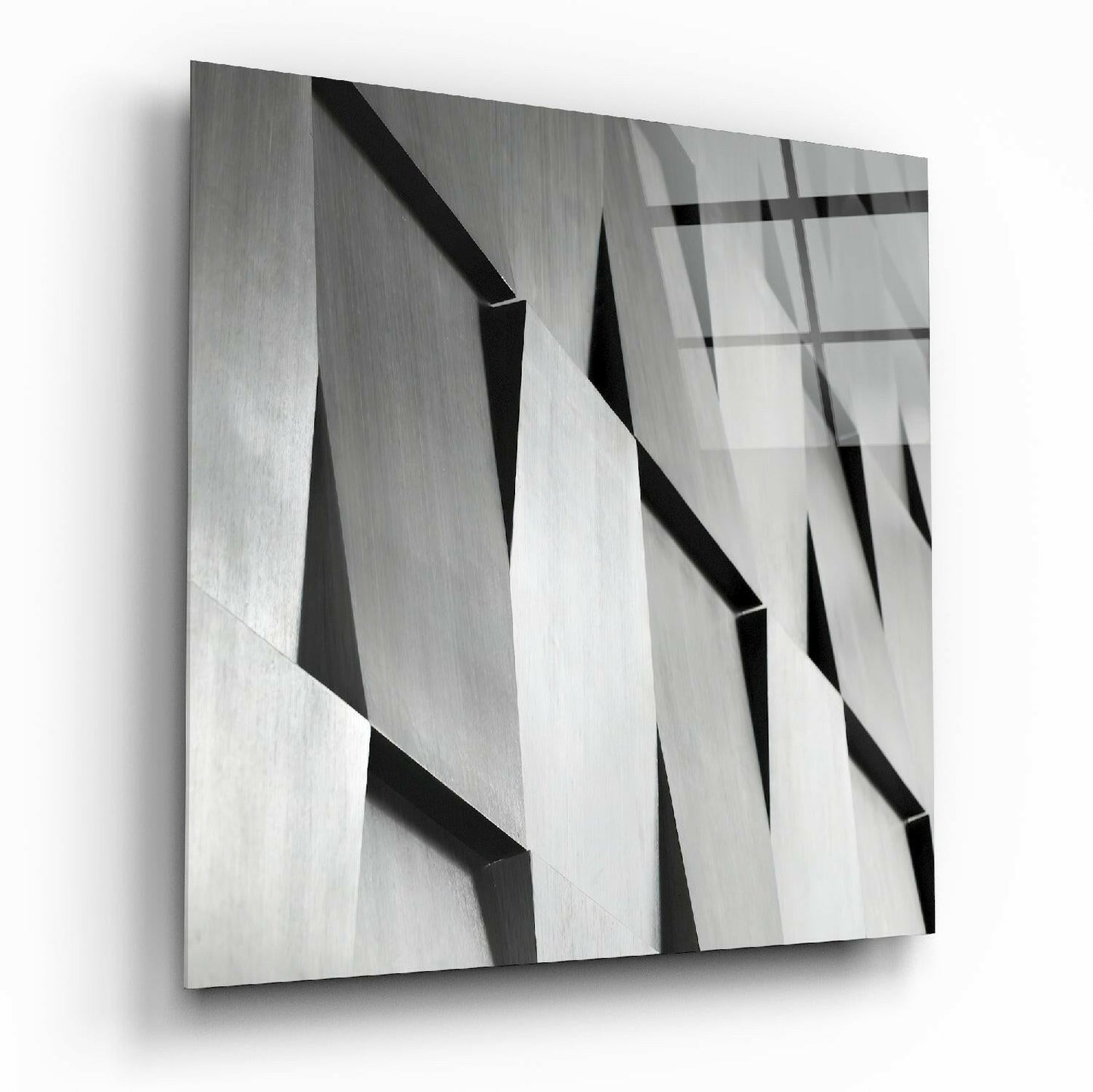 Close-up angled view of textured glass wall art featuring overlapping geometric planes in grayscale with sharp shadows and reflections.