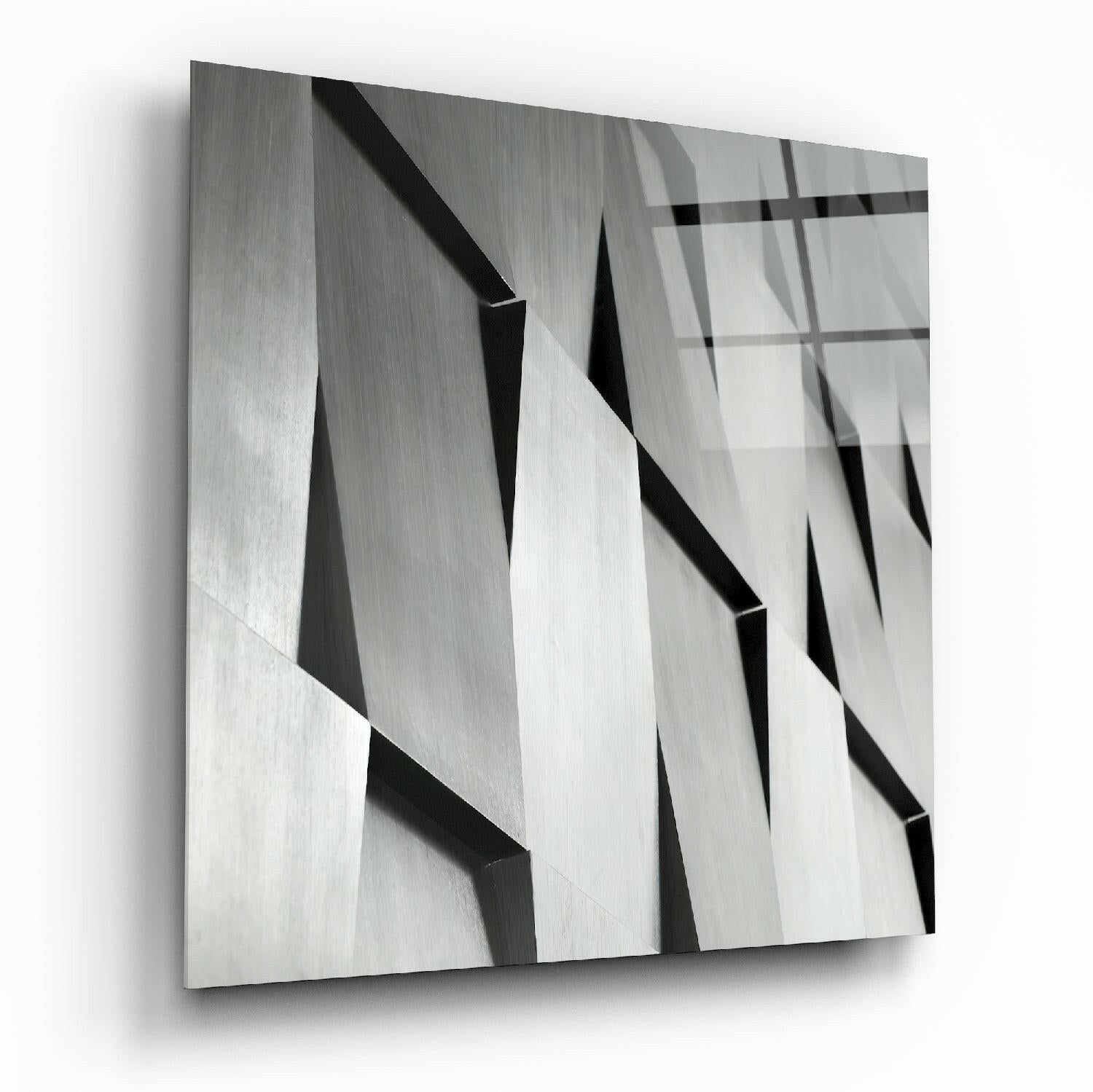 Close-up angled view of textured glass wall art featuring overlapping geometric planes in grayscale with sharp shadows and reflections.
