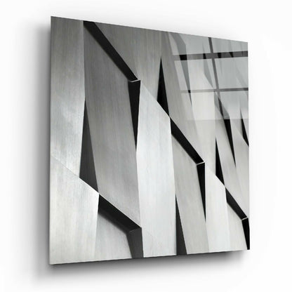 Close-up angled view of textured glass wall art featuring overlapping geometric planes in grayscale with sharp shadows and reflections.