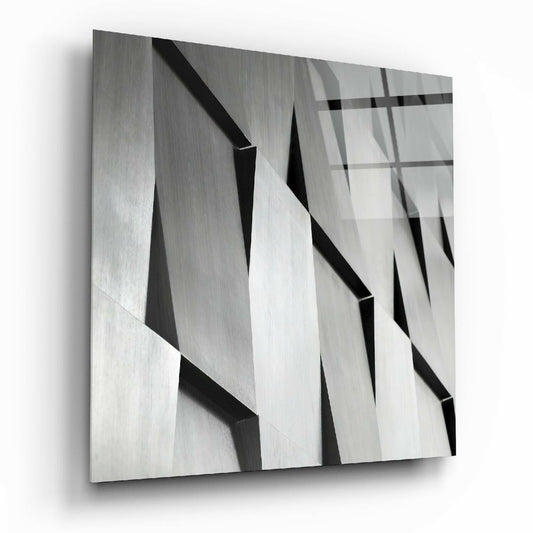Close-up angled view of textured glass wall art featuring overlapping geometric planes in grayscale with sharp shadows and reflections.