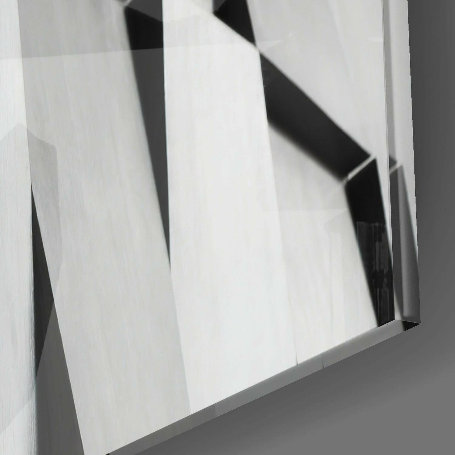 Close-up angled view of translucent glass panels with black geometric shapes and white surface reflections.
