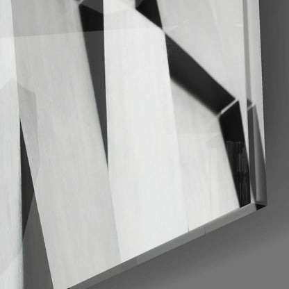Close-up angled view of translucent glass panels with black geometric shapes and white surface reflections.