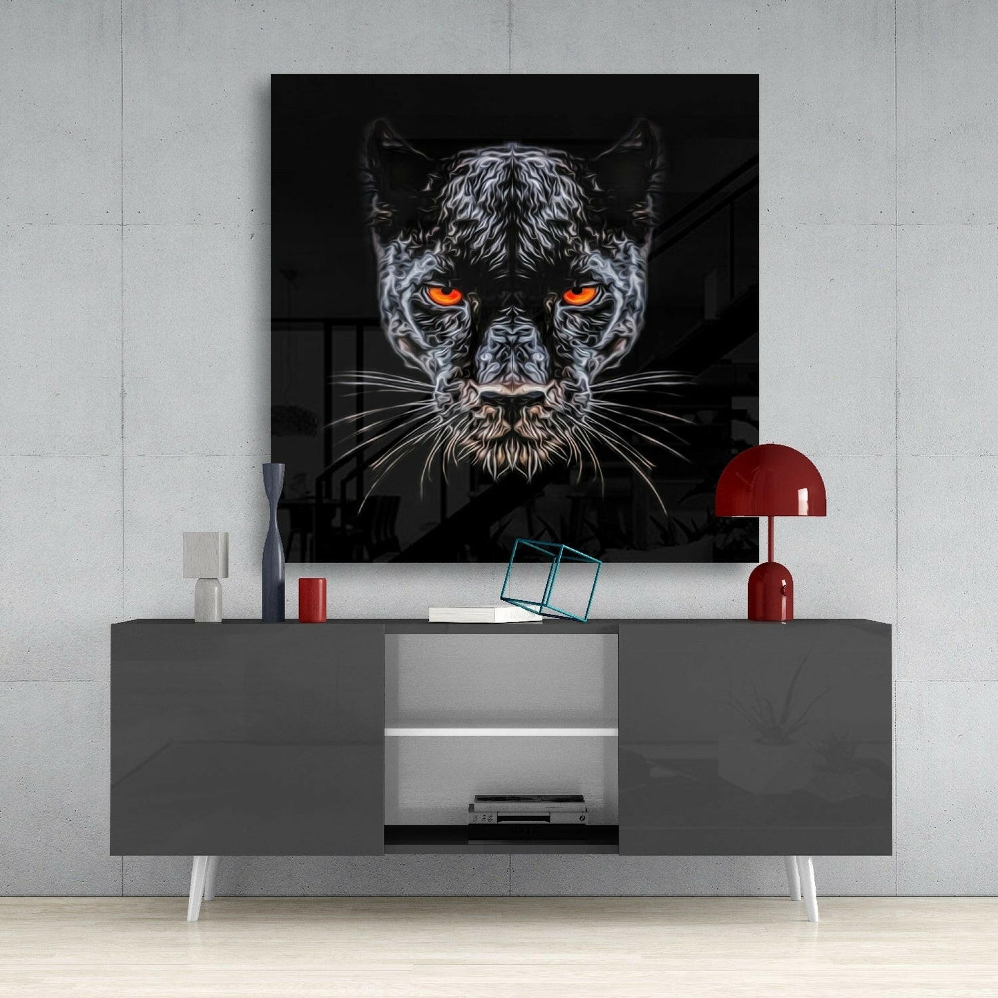 Black panther glass wall art with glowing orange eyes displayed above gray media console with red lamp and decorative accessories.