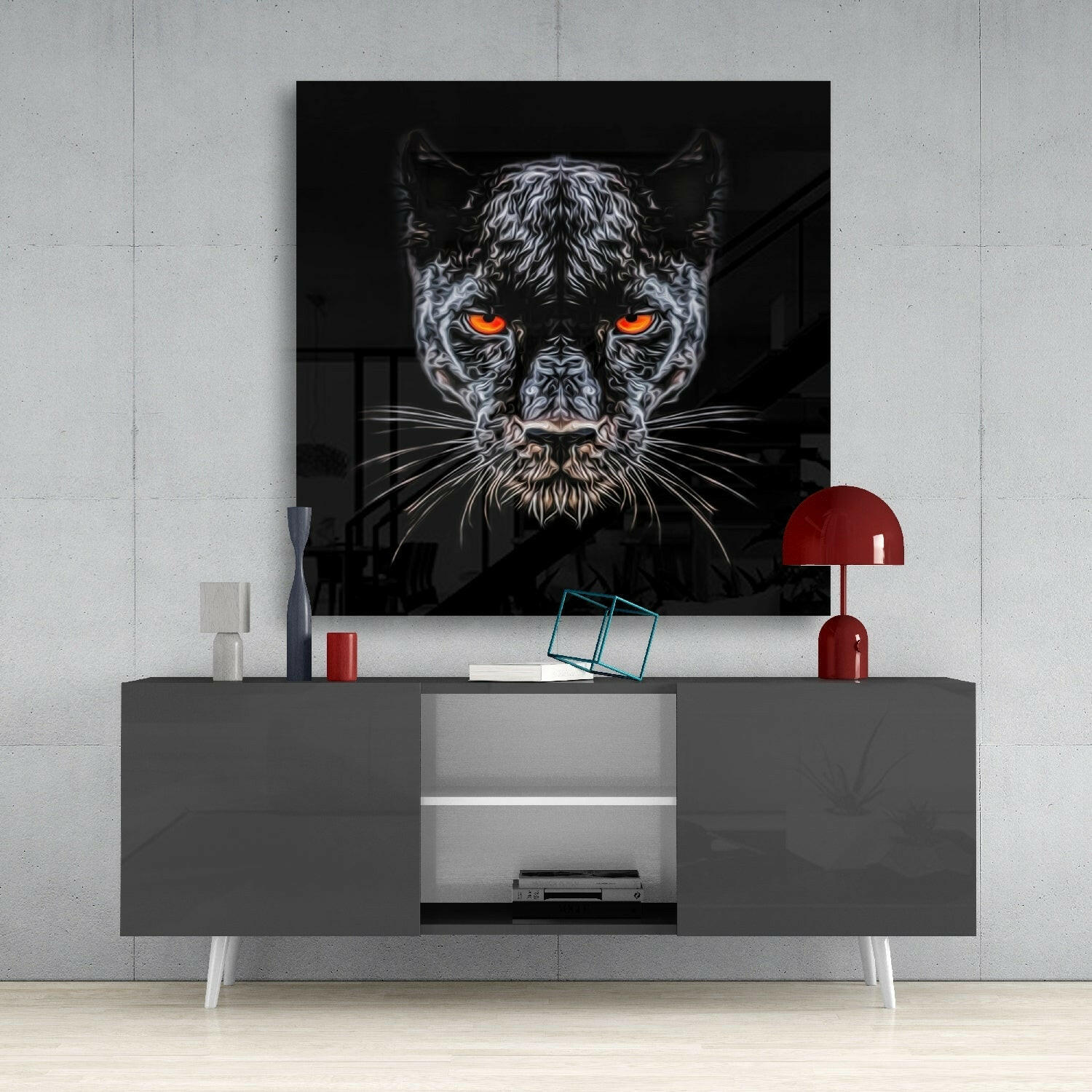 Black panther glass wall art with glowing orange eyes displayed above gray media console with red lamp and decorative accessories.