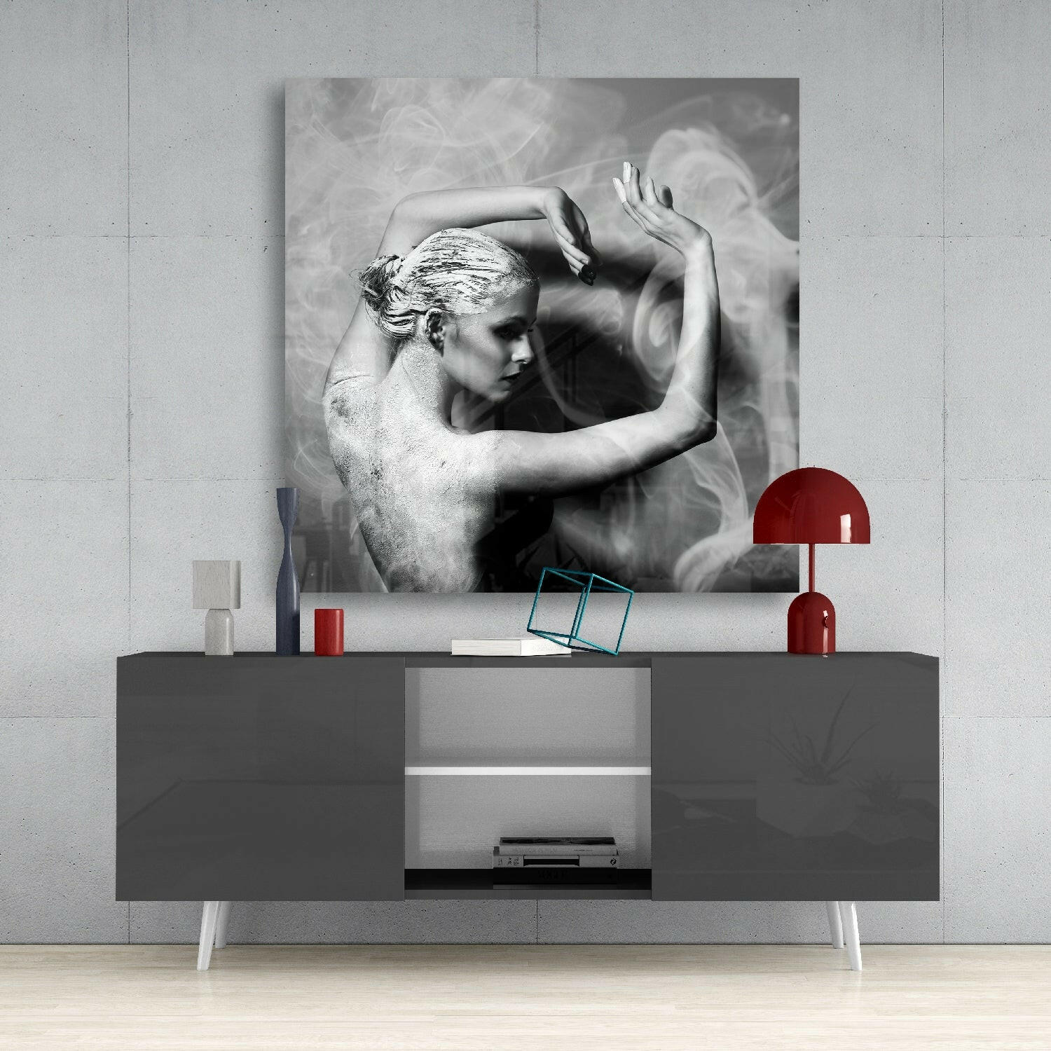 Black and white glass wall art depicting a shirtless man with styled hair and raised arms, displayed above a gray media console with red accents.