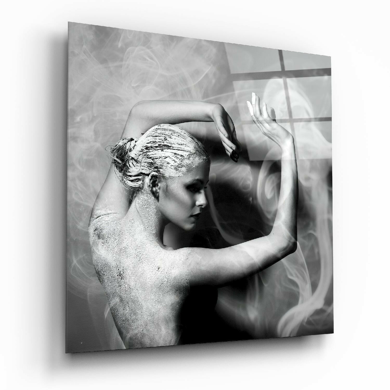 Black and white glass wall art depicting a shirtless figure in profile with gold leaf on hair, hands raised, against textured background with window shadows.