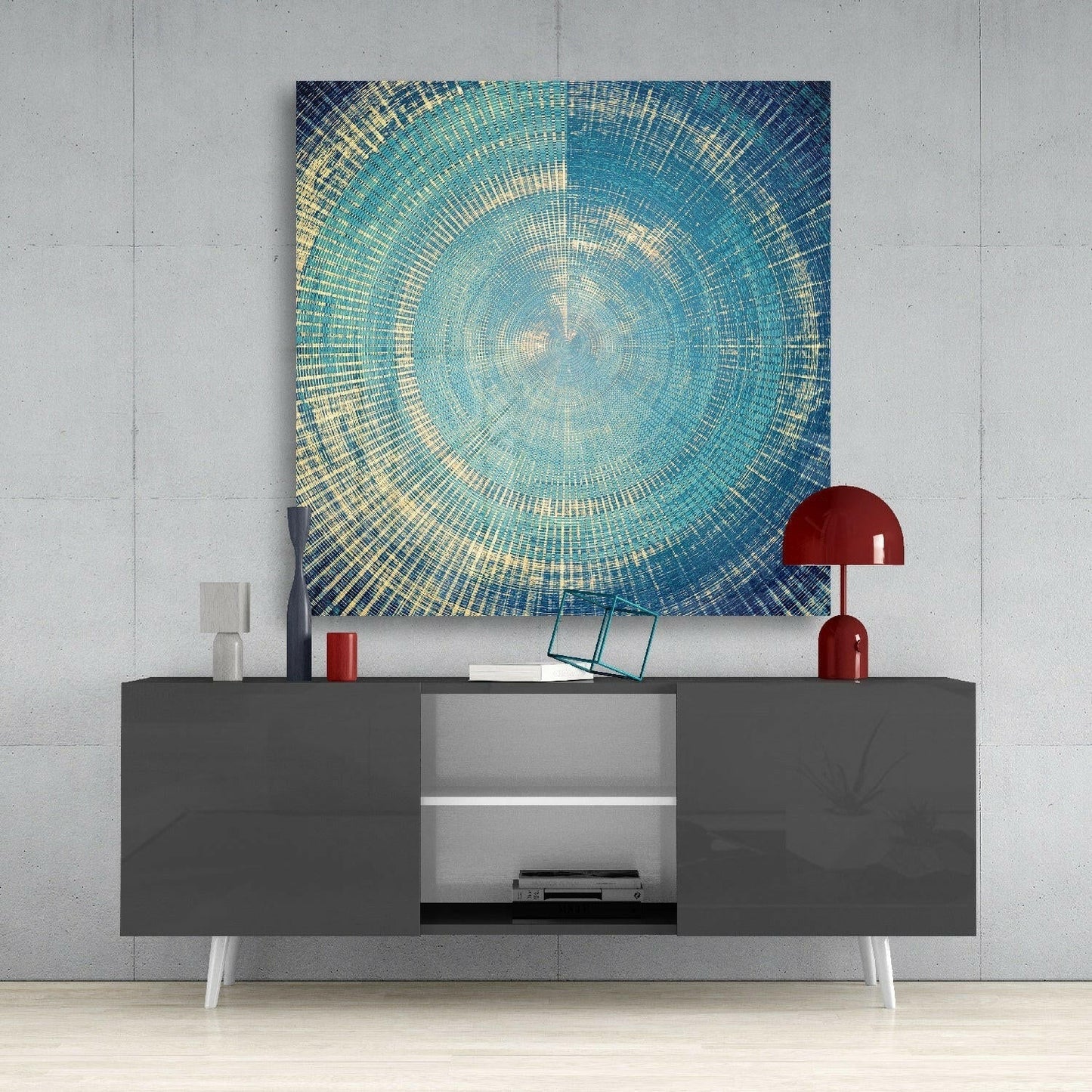 Modern living room setup featuring a square glass wall art with concentric turquoise and gold circular pattern above a dark gray sideboard with red accents.