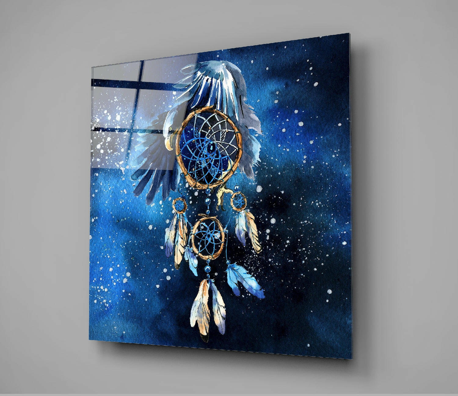 Angled view of glass wall art displaying a dreamcatcher with blue feathers and golden rings against a dark blue starry background.