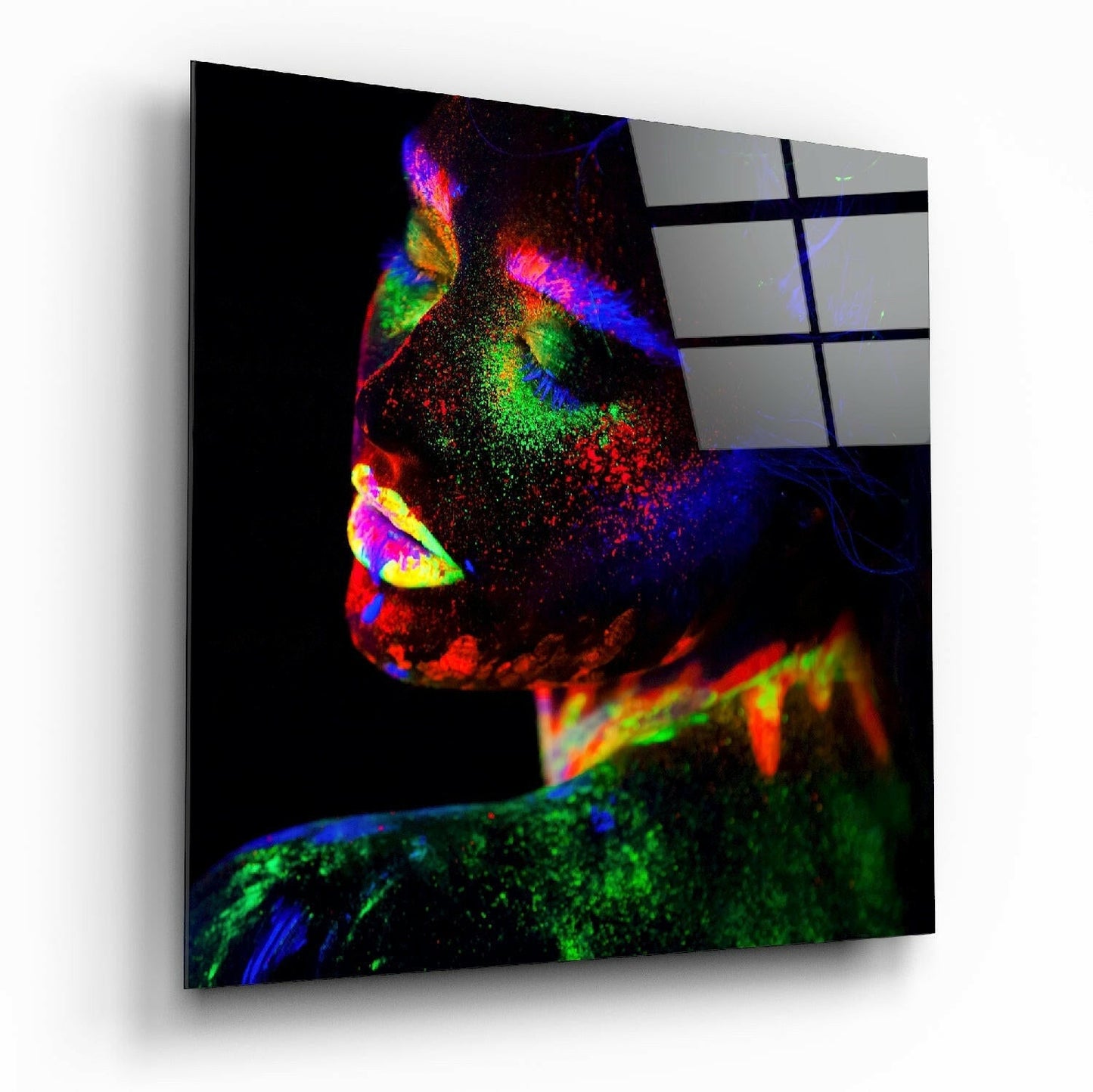 Angled perspective of neon color makeup glass wall art displaying vibrant red, blue, green, and yellow pigments on black background.