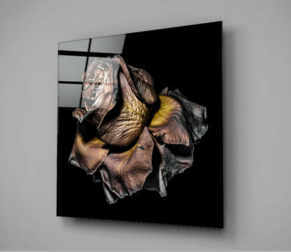 Black glass wall panel displaying a detailed dried rose specimen with brown petals and yellow stamens against dark background.
