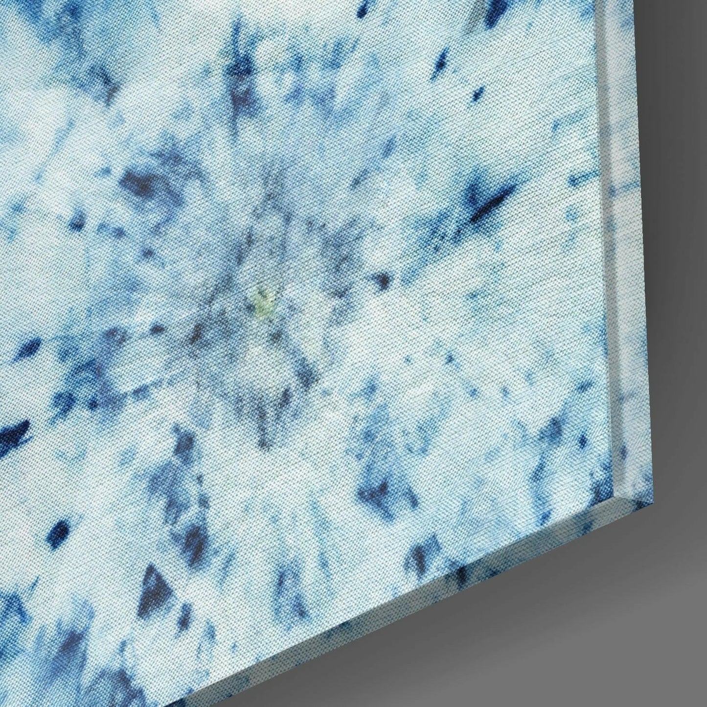 Close-up detail of blue patterned glass wall art showing white base with scattered dark and light blue brushstroke marks.