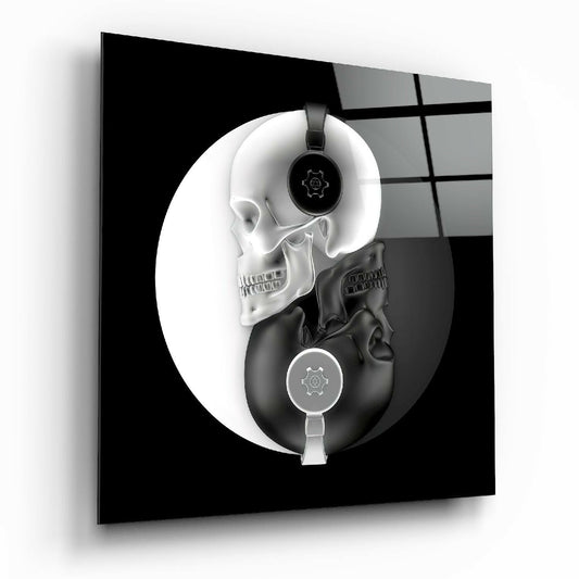 Angled perspective of glass wall art showing white and black skulls arranged in yin-yang composition wearing headphones with gear icons.