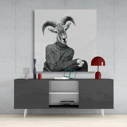 Black and white glass wall art depicting an anthropomorphic antelope in a sweater, displayed above a dark console table with red lamp and accessories.