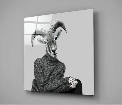 Black and white portrait of antelope head on human figure wearing gray sweater, displayed on glass panel against white wall.