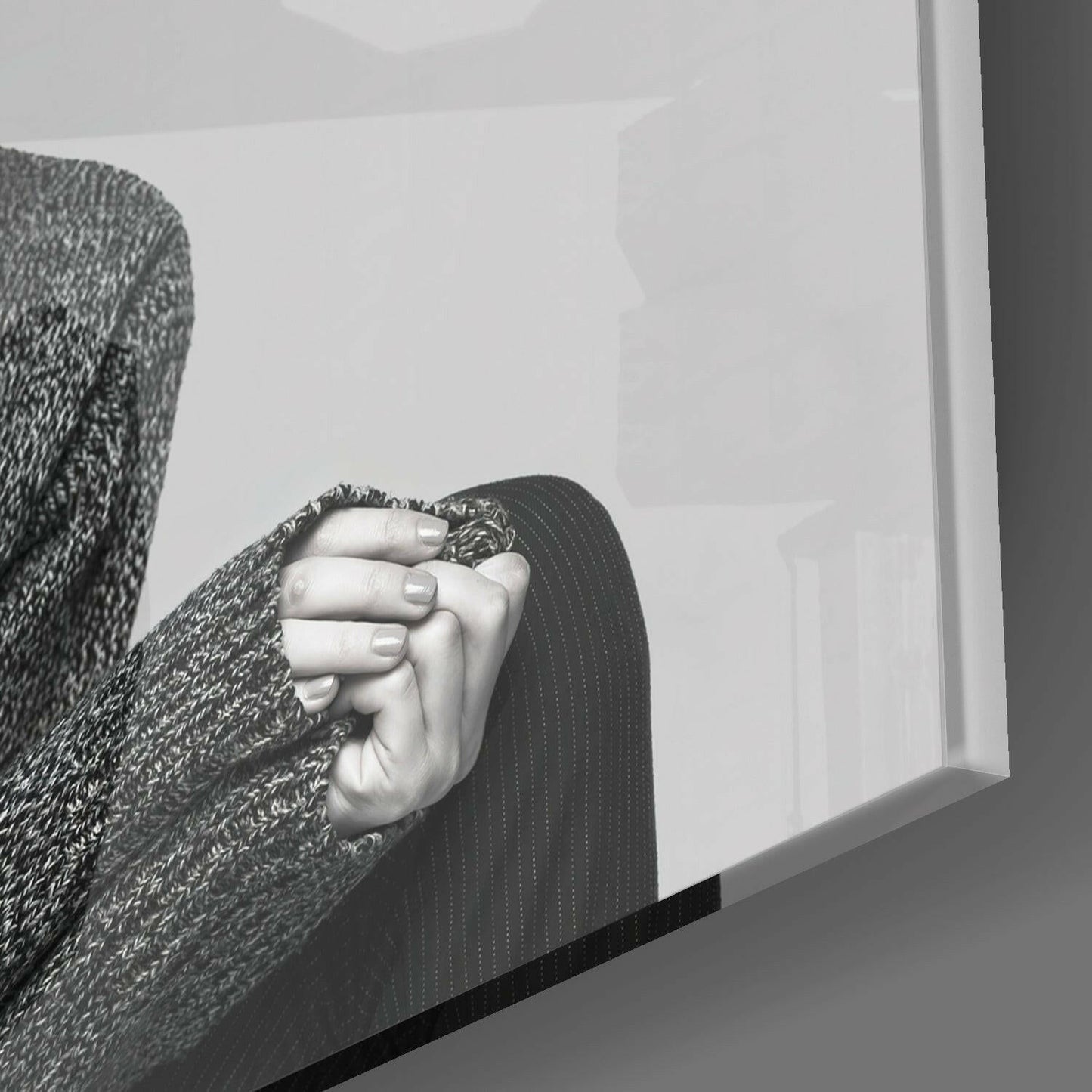 Close-up of hands wearing textured gray sweater and dark pinstriped garment, holding frosted glass art depicting antelope profile.