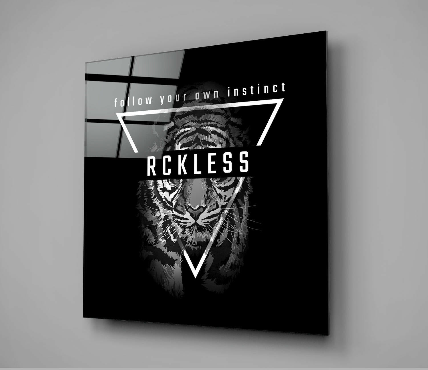 Black glass wall art panel displaying a tiger's face within white triangular frames, with white text reading "follow your own instinct" and "RCKLESS" against dark background.
