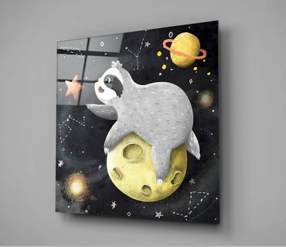 Angled view of glass wall art depicting a white sleeping creature on a yellow moon surrounded by planets and stars against a black background.