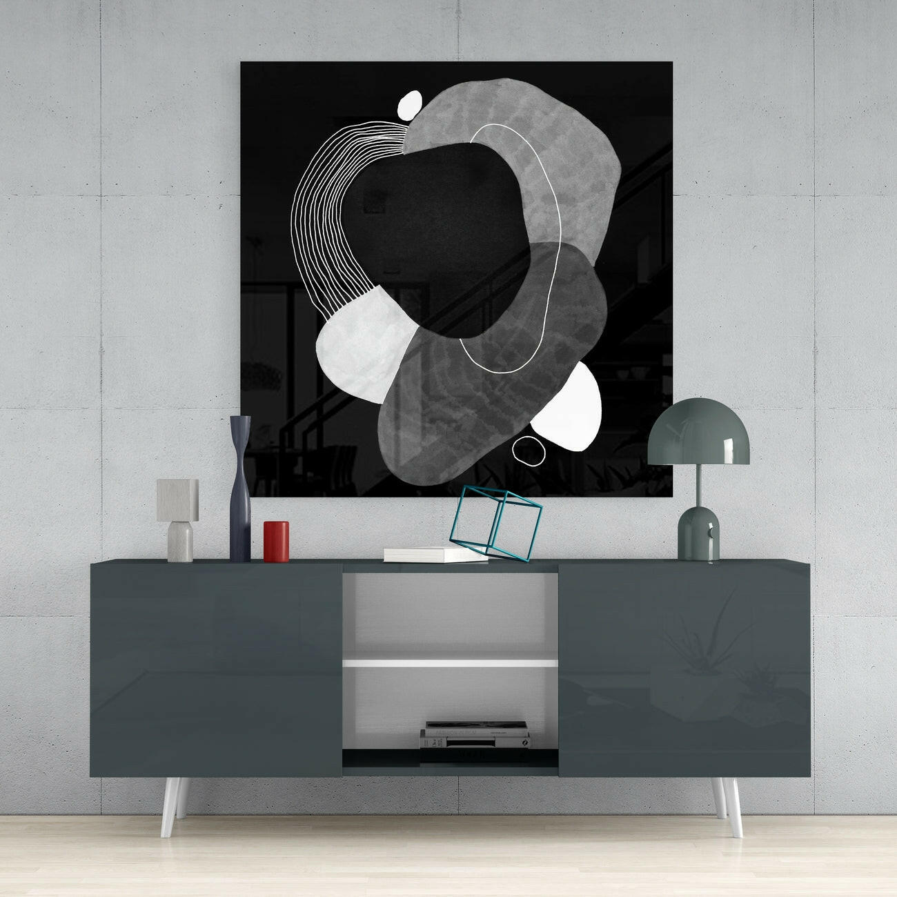 Black glass wall art with abstract geometric shapes in white and gray displayed above a dark console table in a modern interior setting.