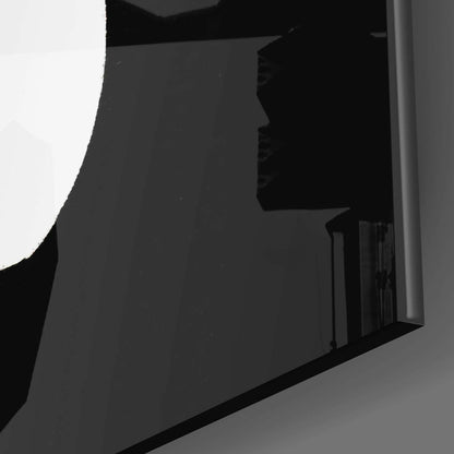 Close-up angled view of black glass wall art panel showing glossy surface texture and curved edge detail against white background.