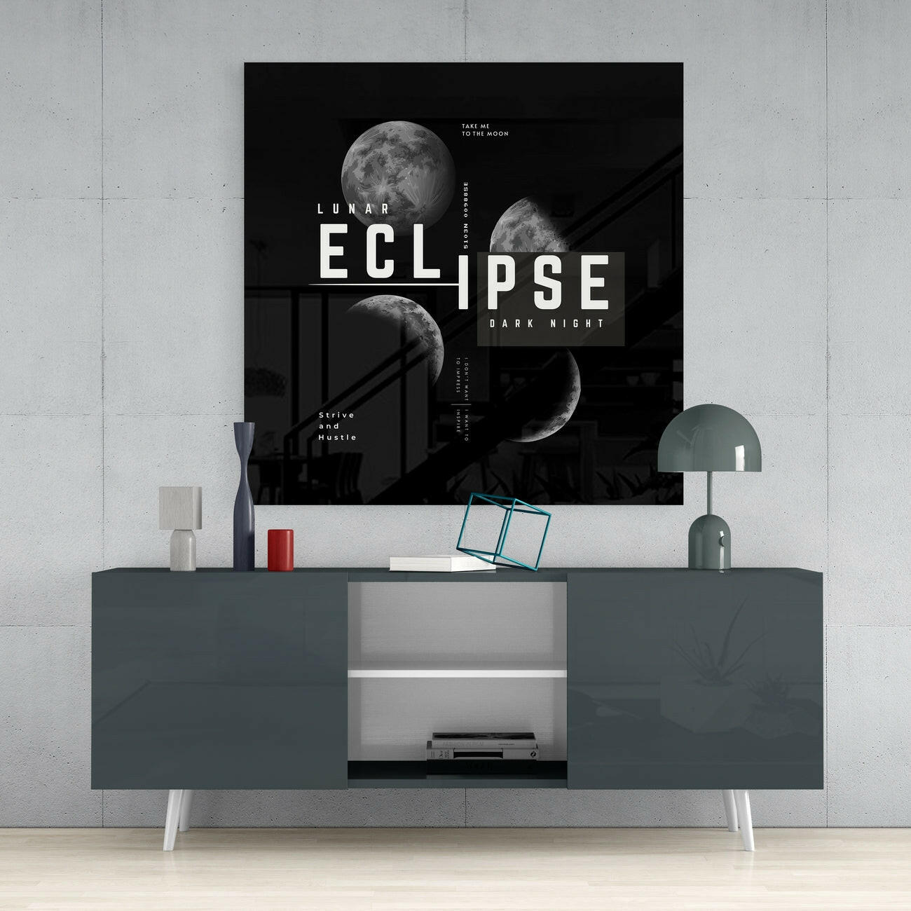 Black lunar eclipse glass wall art with white typography displayed above a dark gray dresser in a minimalist interior setting.