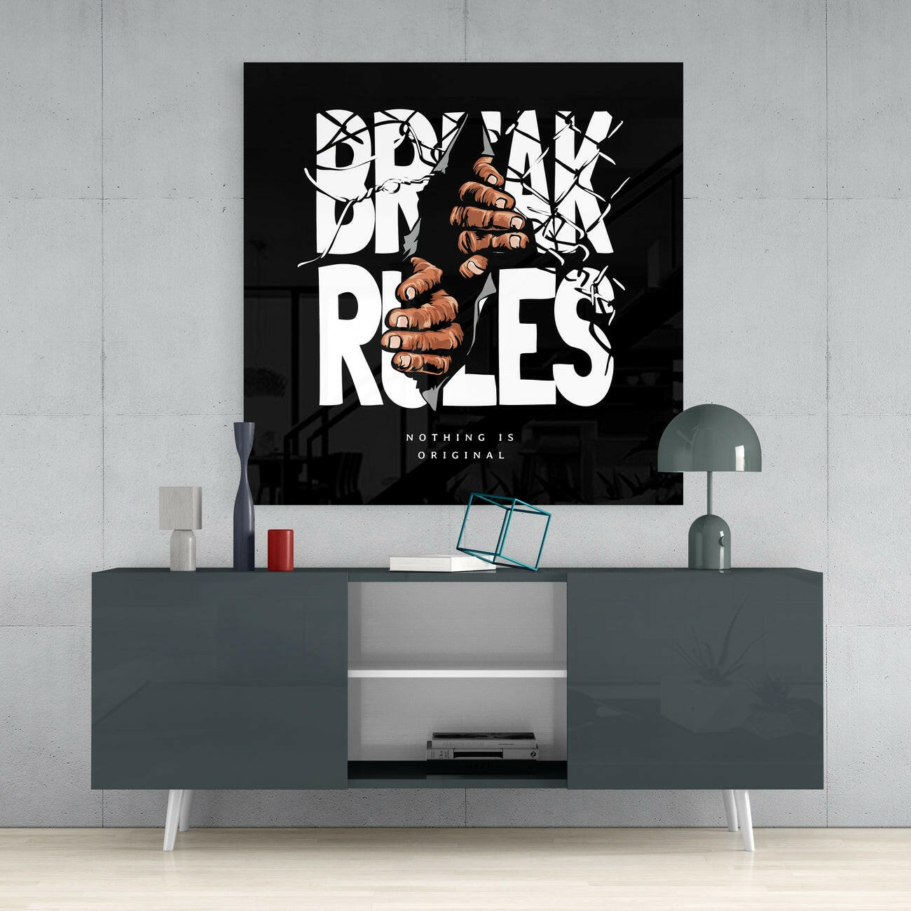 Black glass wall art with white bold typography and brown fist illustration displaying "Break Rules" tagline mounted above gray media console.