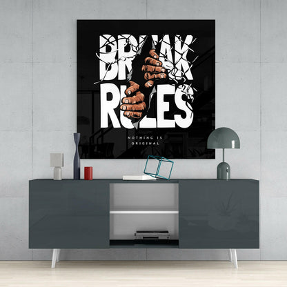 Black glass wall art with white bold typography and brown fist illustration displaying "Break Rules" tagline mounted above gray media console.