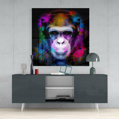 Colorful glass wall art of a chimpanzee wearing headphones and sunglasses displayed above a gray media console in a modern interior setting.