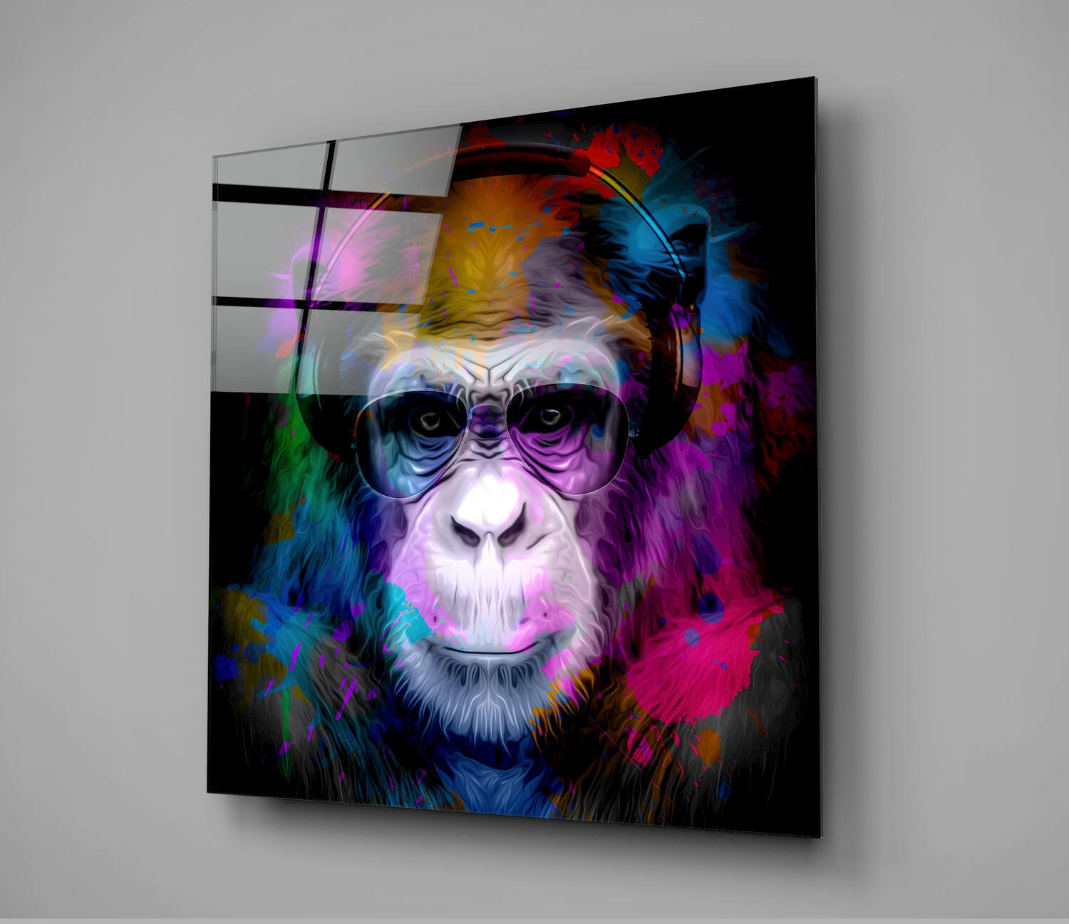 Colorful glass wall art featuring a bespectacled monkey's face with vibrant neon blue, pink, magenta, and gold splashes against black background, displayed at an angle.