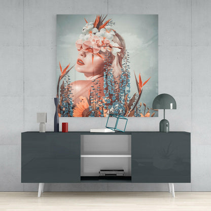 Glass wall art featuring a woman's profile surrounded by coral and white flowers with blue-green foliage, displayed above a dark console table.