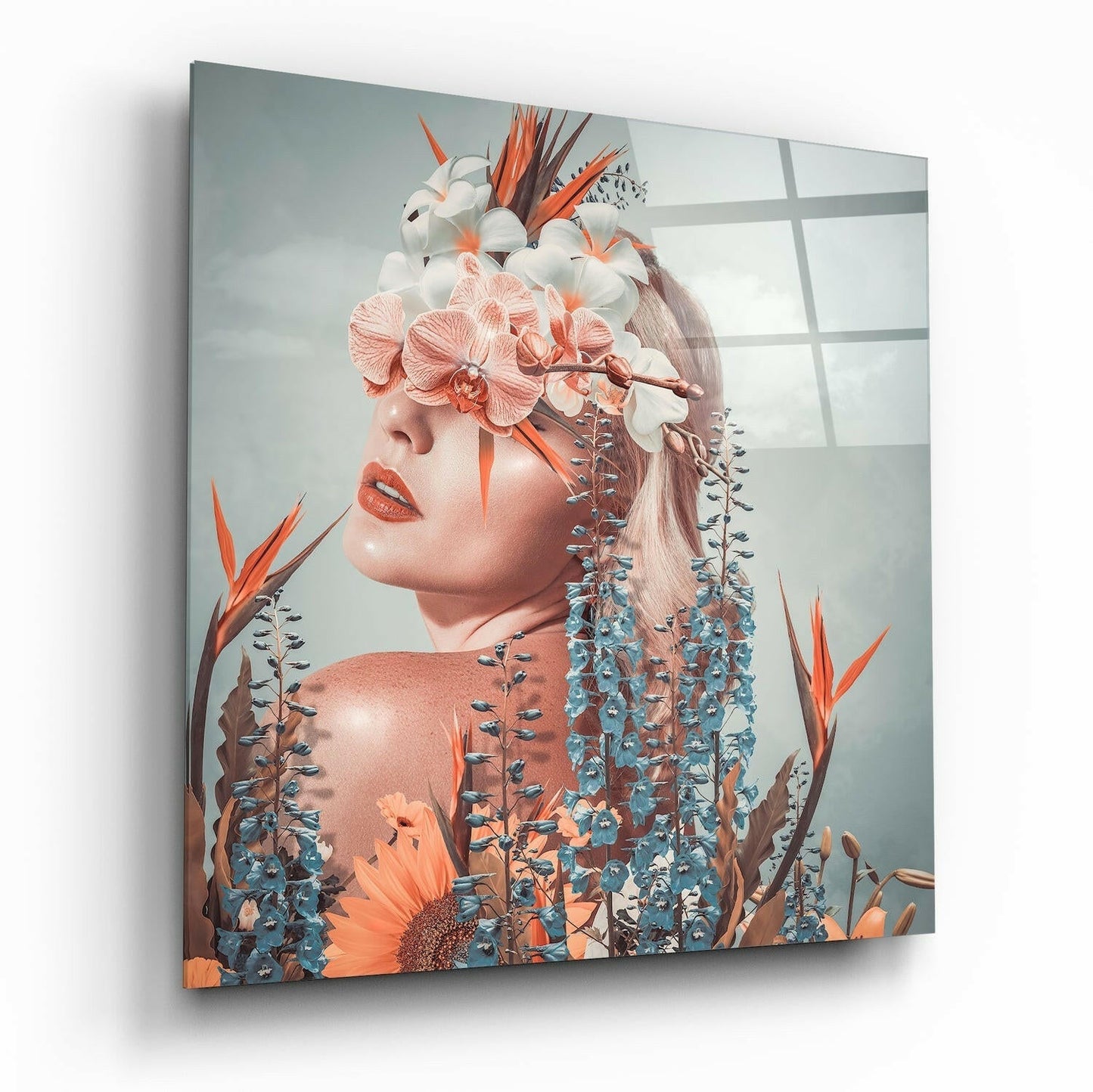 Glass wall art displaying a woman's profile surrounded by pink orchids, white flowers, and blue-green foliage against a soft gray background.
