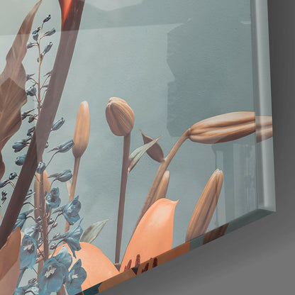 Close-up detail of glass wall art showing orange tulip buds and blue flowering stems against translucent blue-grey background with window light.