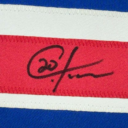Close-up of handwritten black signature on red stripe of blue, white, and red striped fabric jersey.