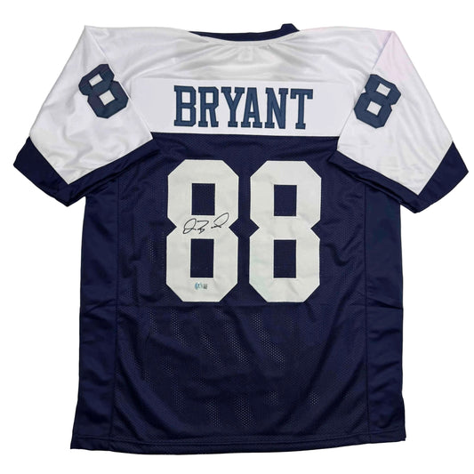 Navy and white Dallas Cowboys Thanksgiving Day jersey number 88 with "BRYANT" nameplate and autograph, displayed flat on white background.