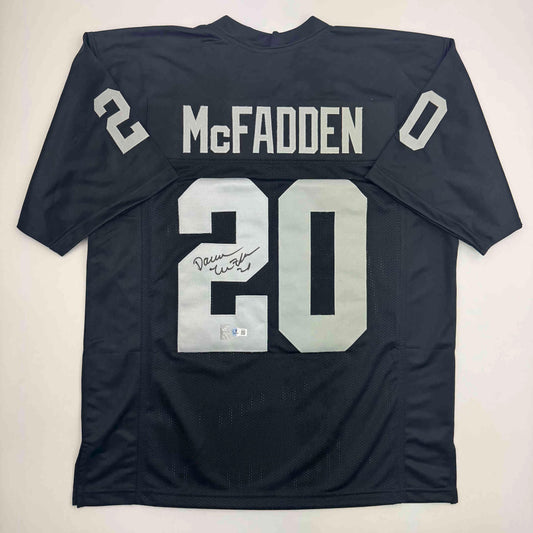 Back view of black McFadden #20 football jersey with autographed signature and Beckett authentication sticker visible on white numbering.