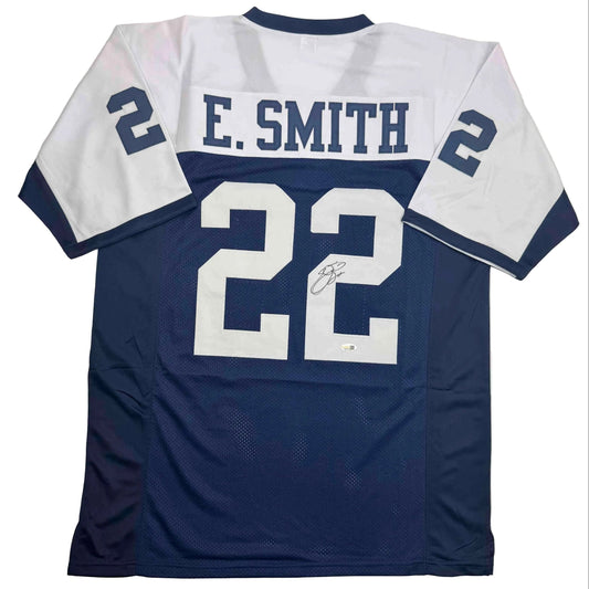 Back view of navy and white Dallas Cowboys jersey number 22 with "E. SMITH" nameplate and autograph visible.