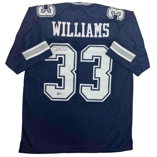 Back view of navy blue football jersey with white "WILLIAMS" name and number "33" with autograph signature visible.