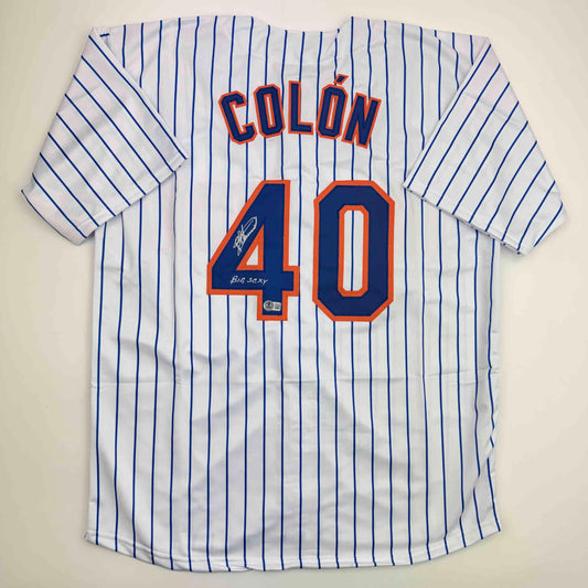 White pinstriped baseball jersey with "COLON" and number "40" in blue and orange, displaying handwritten autograph and "Big Sexy" inscription on front.