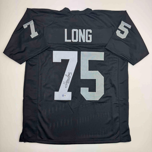 Back view of black football jersey with white "LONG" nameplate and "75" number, signed in black ink, displayed flat against white background.