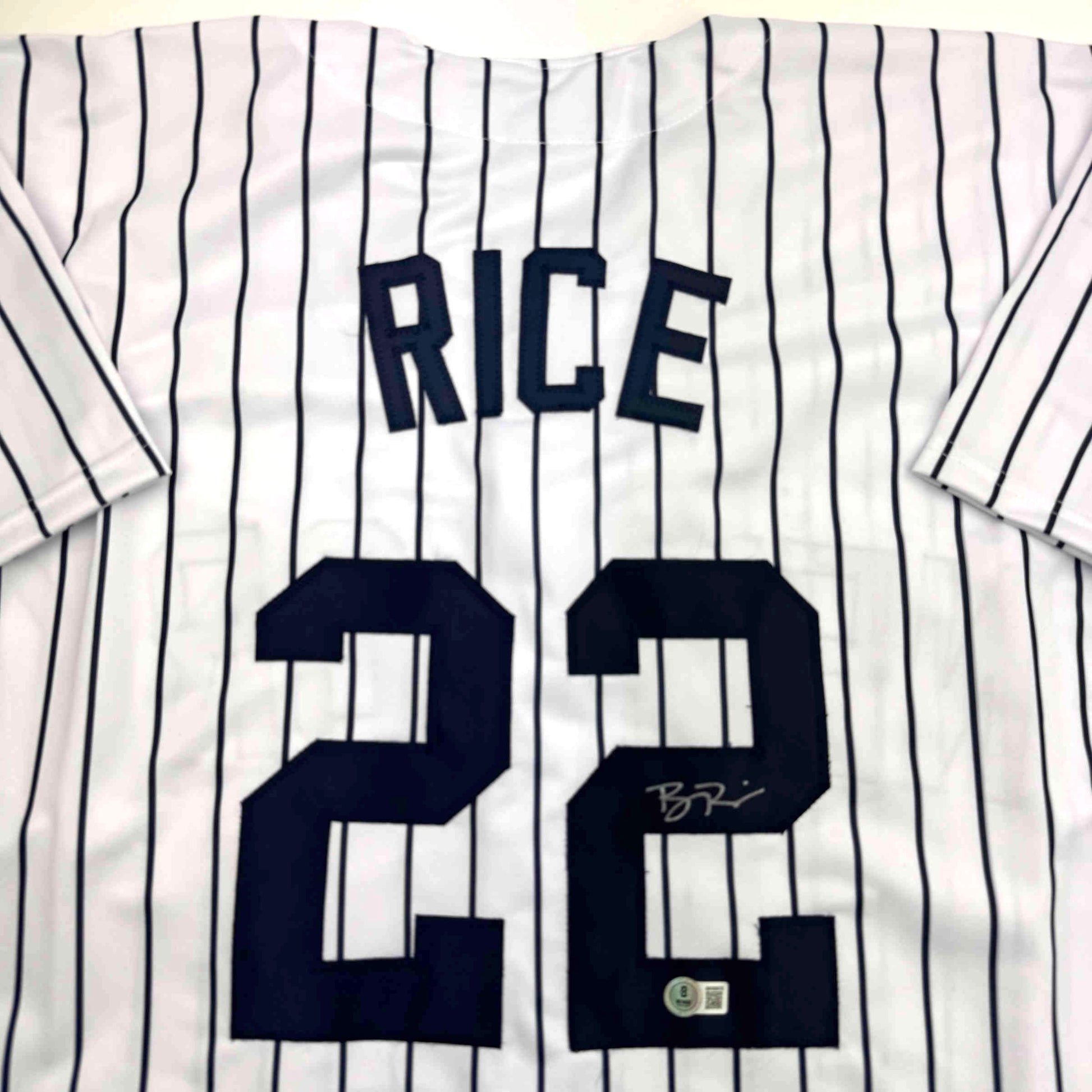 White pinstriped baseball jersey with "RICE" and number "28" in navy blue, displayed flat with visible signature and authentication sticker.