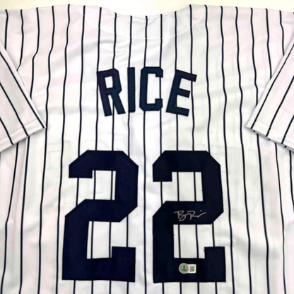 White pinstriped baseball jersey with "RICE" and number "28" in navy blue, displayed flat with visible signature and authentication sticker.