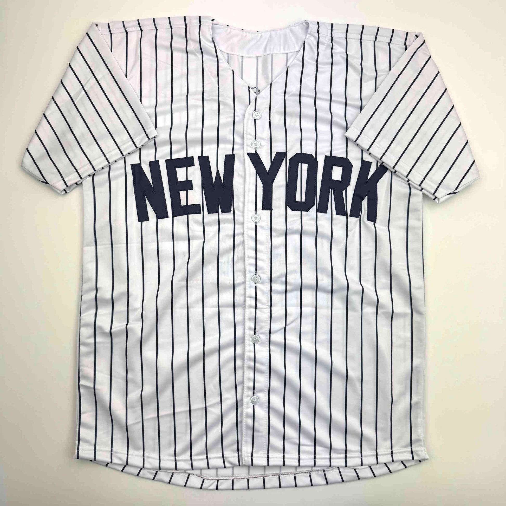 White pinstriped New York baseball jersey with navy blue vertical stripes and "NEW YORK" text across chest, displayed flat against cream background.