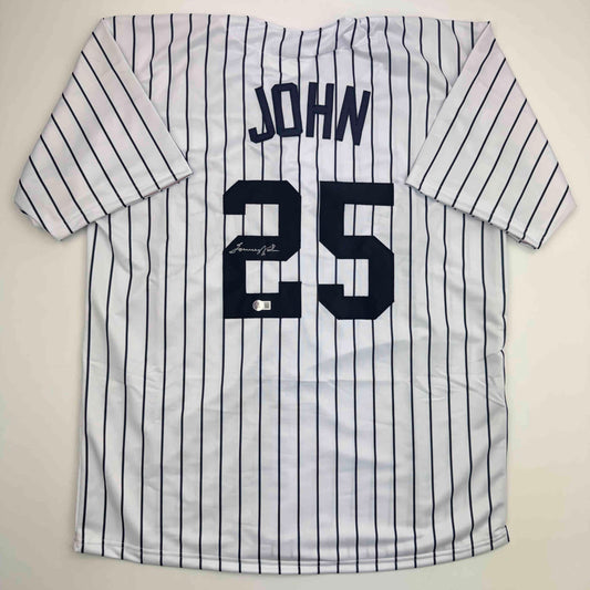 Flat lay of white pinstriped baseball jersey with "JOHN" and number "25" in navy, featuring visible autograph on the number.