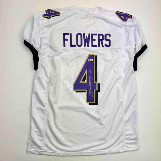 Back view of white Baltimore Ravens football jersey number 4 with "FLOWERS" nameplate and purple and gold trim.