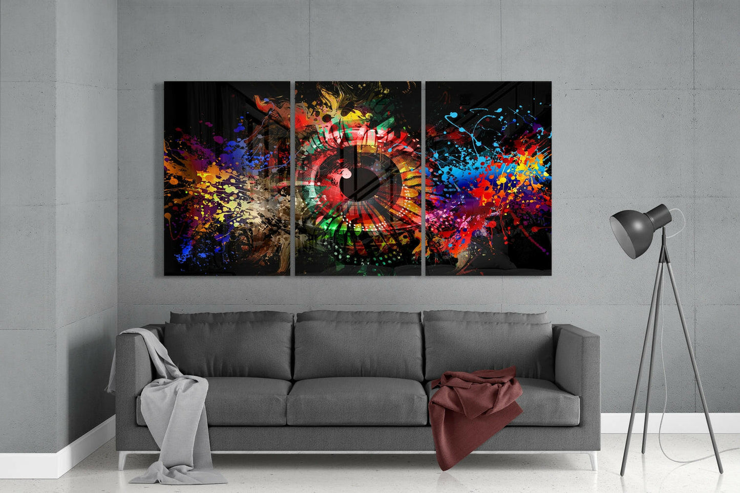 Three-panel colorful glass wall art with vibrant paint splashes and a clock face displayed above a gray sofa in a modern living room.