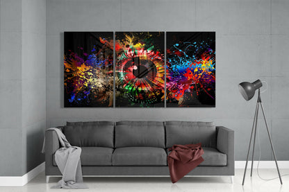 Three-panel colorful glass wall art with vibrant paint splashes and a clock face displayed above a gray sofa in a modern living room.