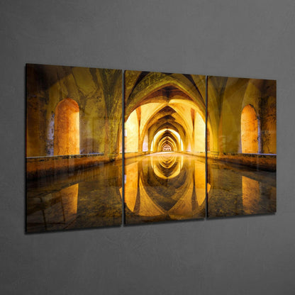Three-panel glass wall art depicting a symmetrical golden archway tunnel with water reflection and warm yellow lighting.