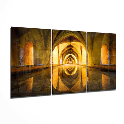 Three-panel triptych showing a symmetrical archway tunnel with golden stone columns reflected in still water below.