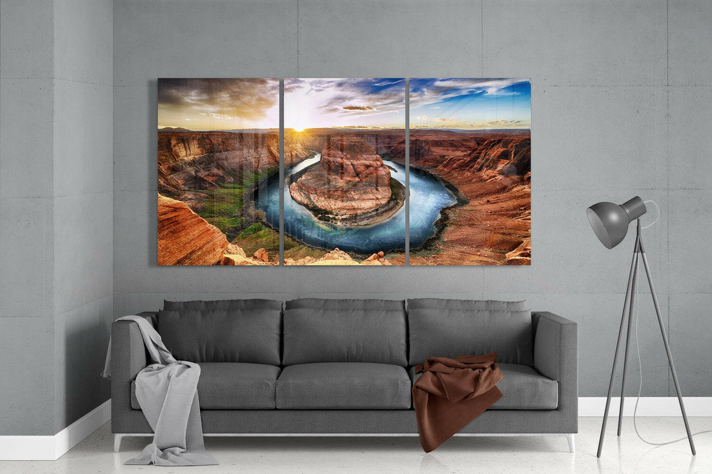 Three-panel glass wall art displaying Horseshoe Bend canyon landscape installed above gray sofa in minimalist interior.