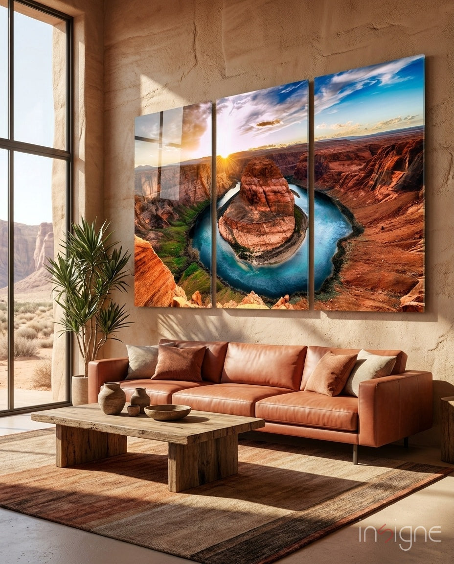 Modern living room with rust-colored leather sofa displaying three-panel glass wall art of Horseshoe Bend canyon landscape at sunset.
